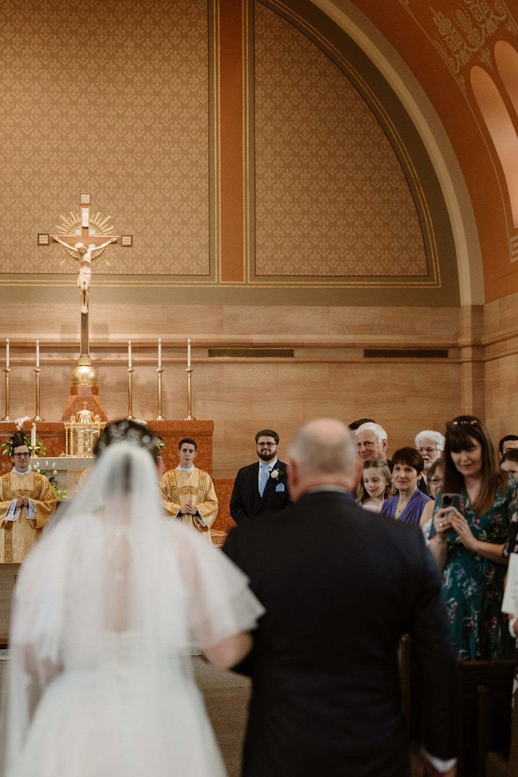 A church wedding ceremony with guests watching under ornate arched ceilings and religious decor.