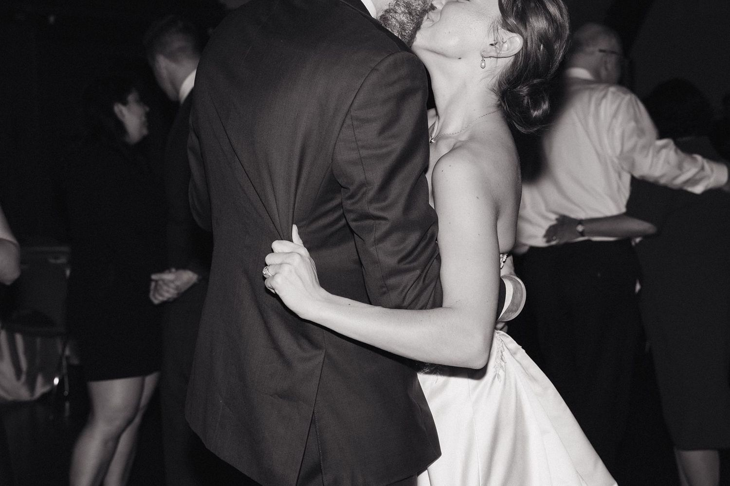 A black and white photo captures a romantic dance moment at a wedding reception.