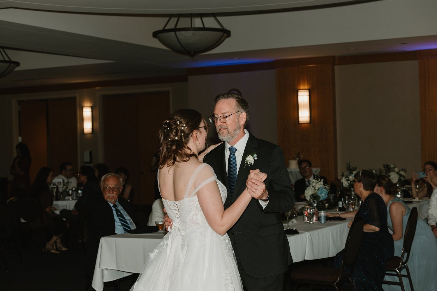 Couple dancing together during their first dance at their wedding reception in an elegantly lit ballroom.