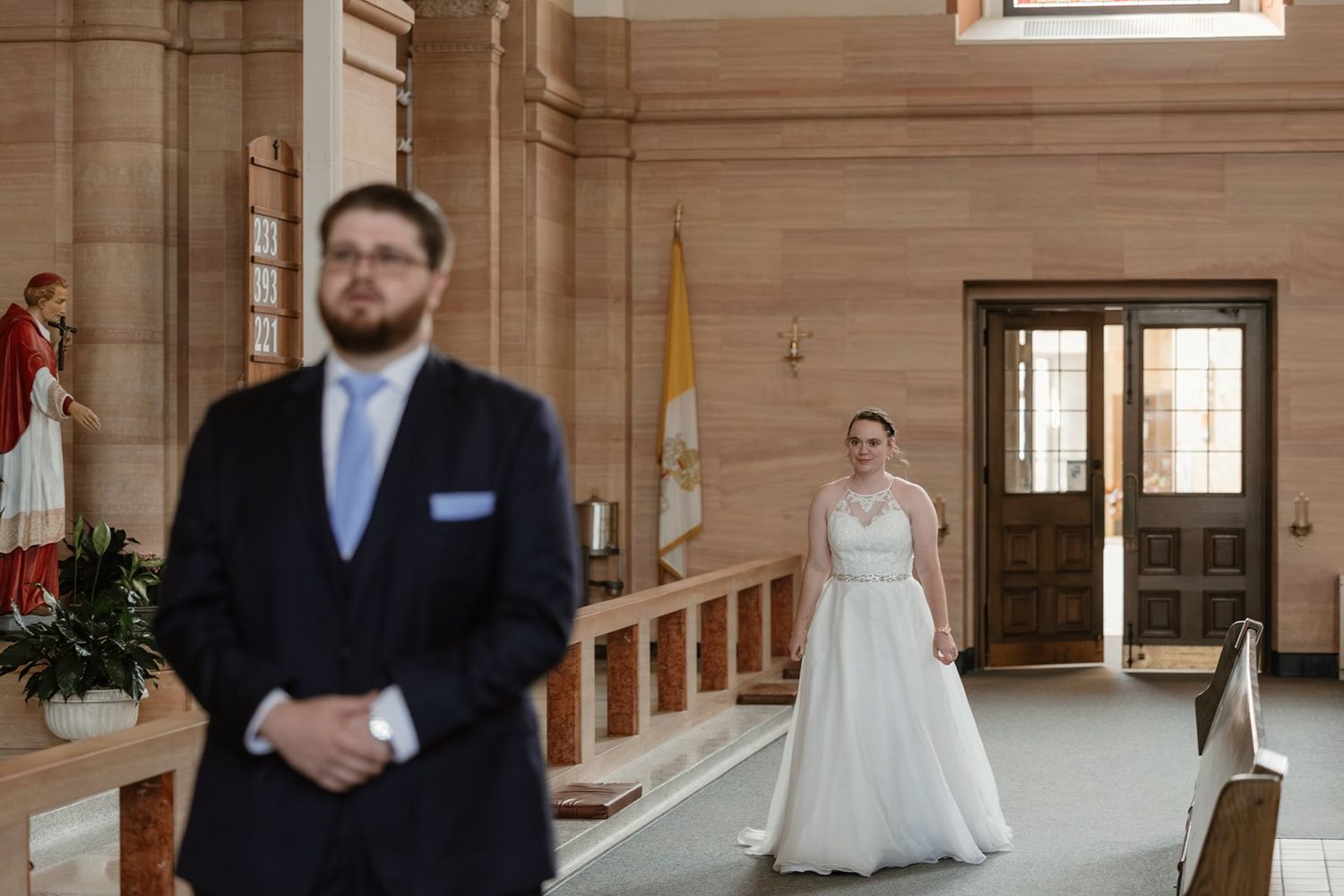 A bride and groom share a candid moment in an elegant marble hallway with ornate architectural details.
