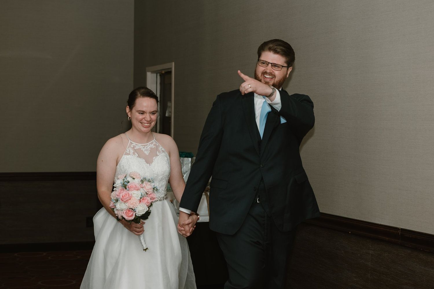 A wedding couple shares a candid moment while walking together in formal attire.