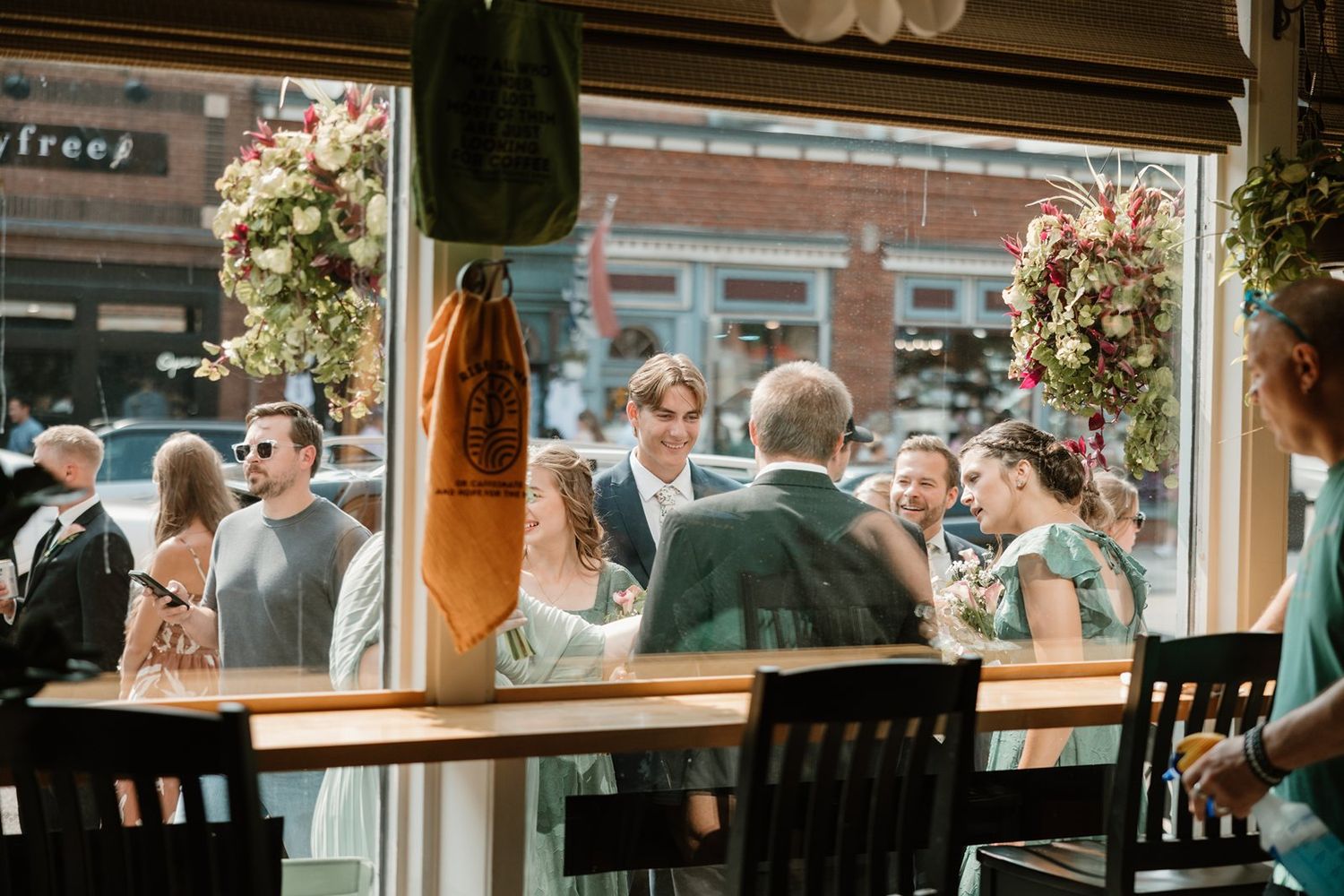 A panoramic view of a crowded outdoor restaurant patio with guests dining under string lights and floral decorations.