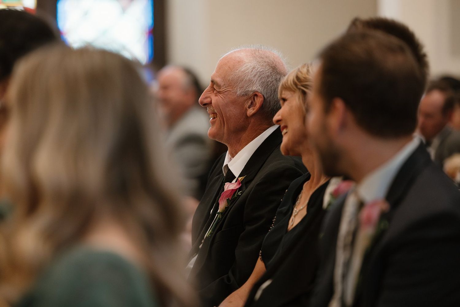 Wedding ceremony guests seated in church pews watching the proceedings.