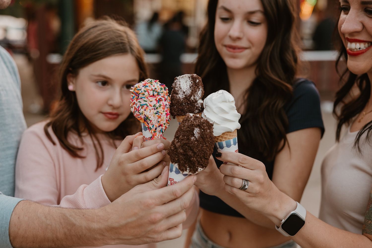 A group of friends gather together holding decorated donuts and pastries at a social event.