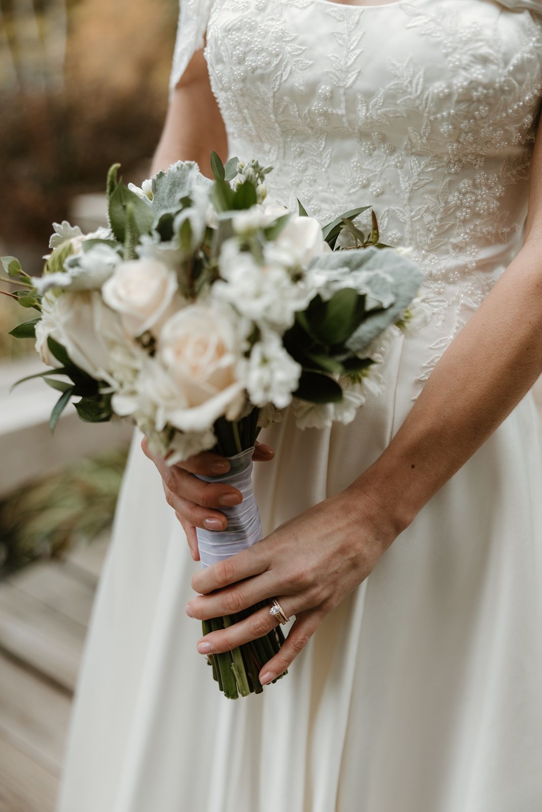 Close-up of bridal bouquet with white roses and delicate greenery.