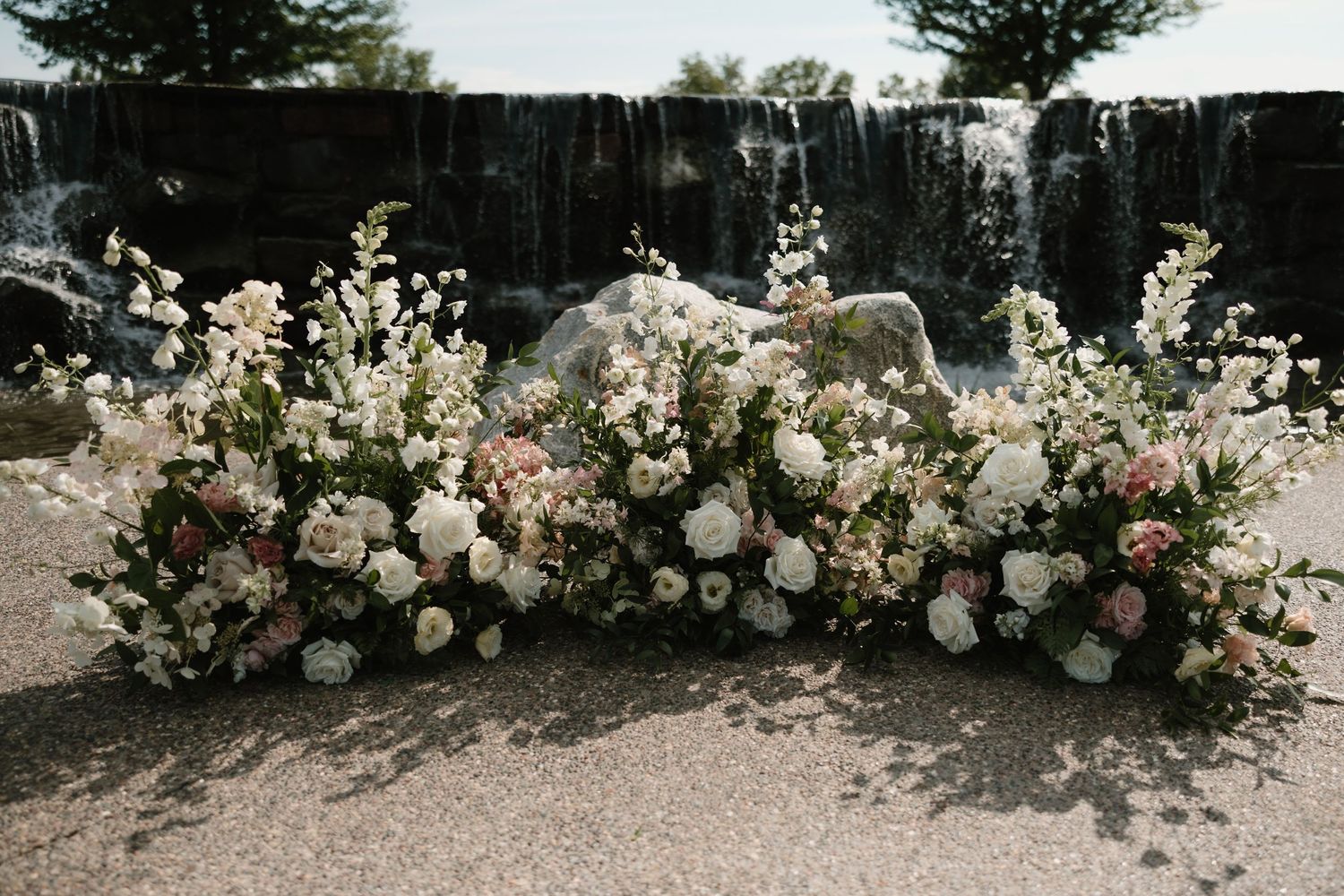 Elegant floral arrangement with white roses and delicate blooms against a dark fence backdrop.