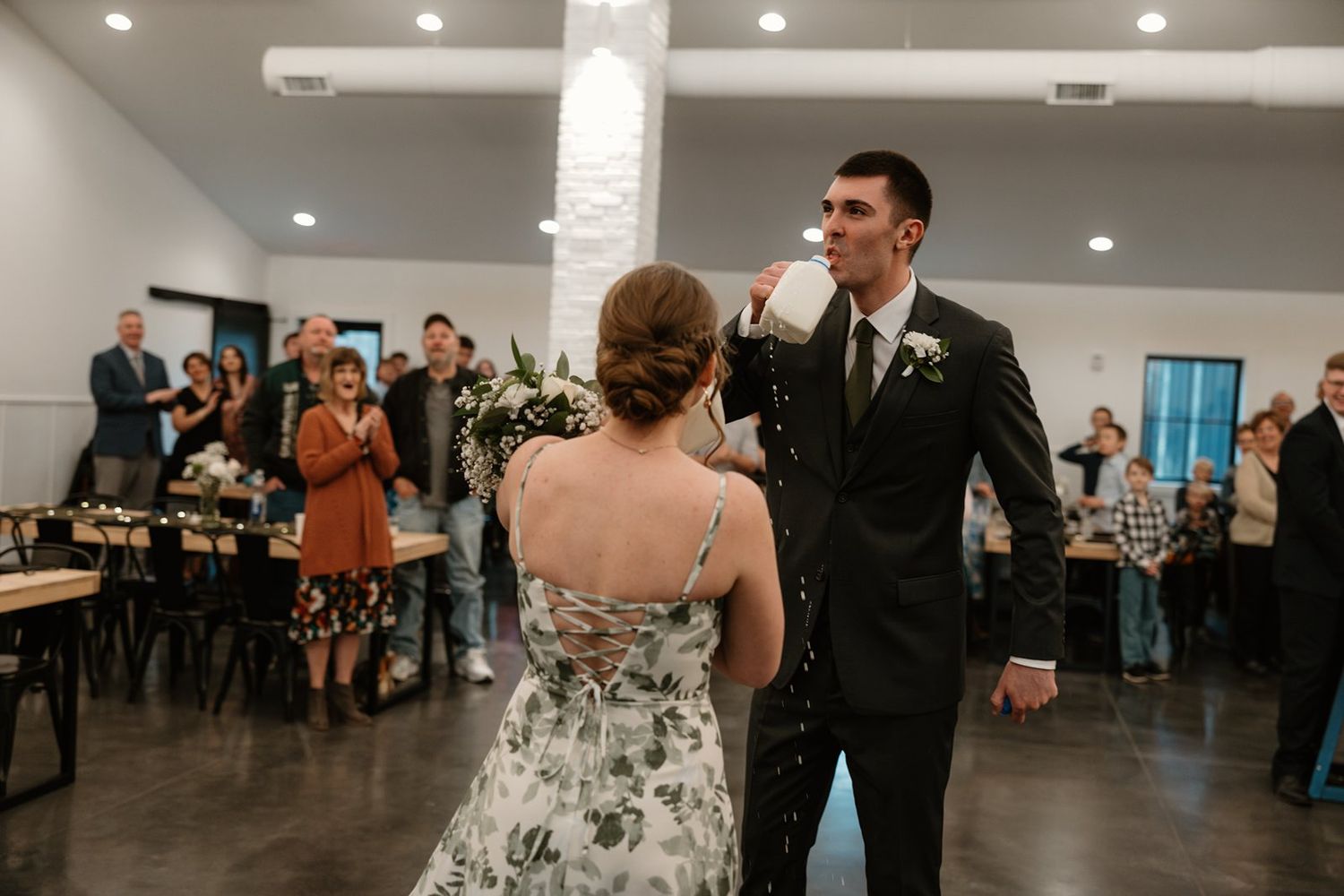 Two people share a tender moment on the dance floor at a wedding reception in an elegant indoor venue.