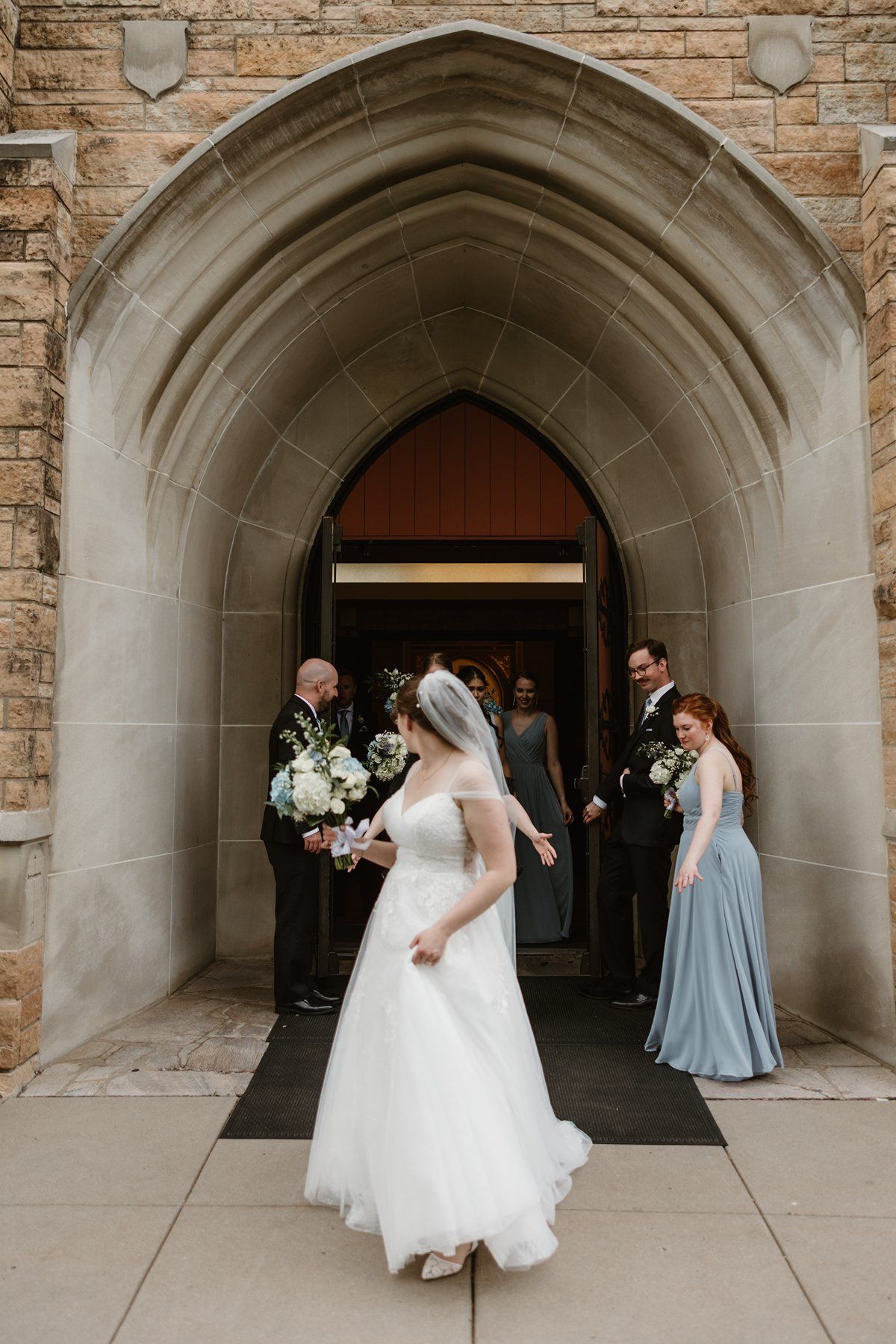 A sequence of wedding photos showing the bridal party walking through a stone arched hallway at a church.