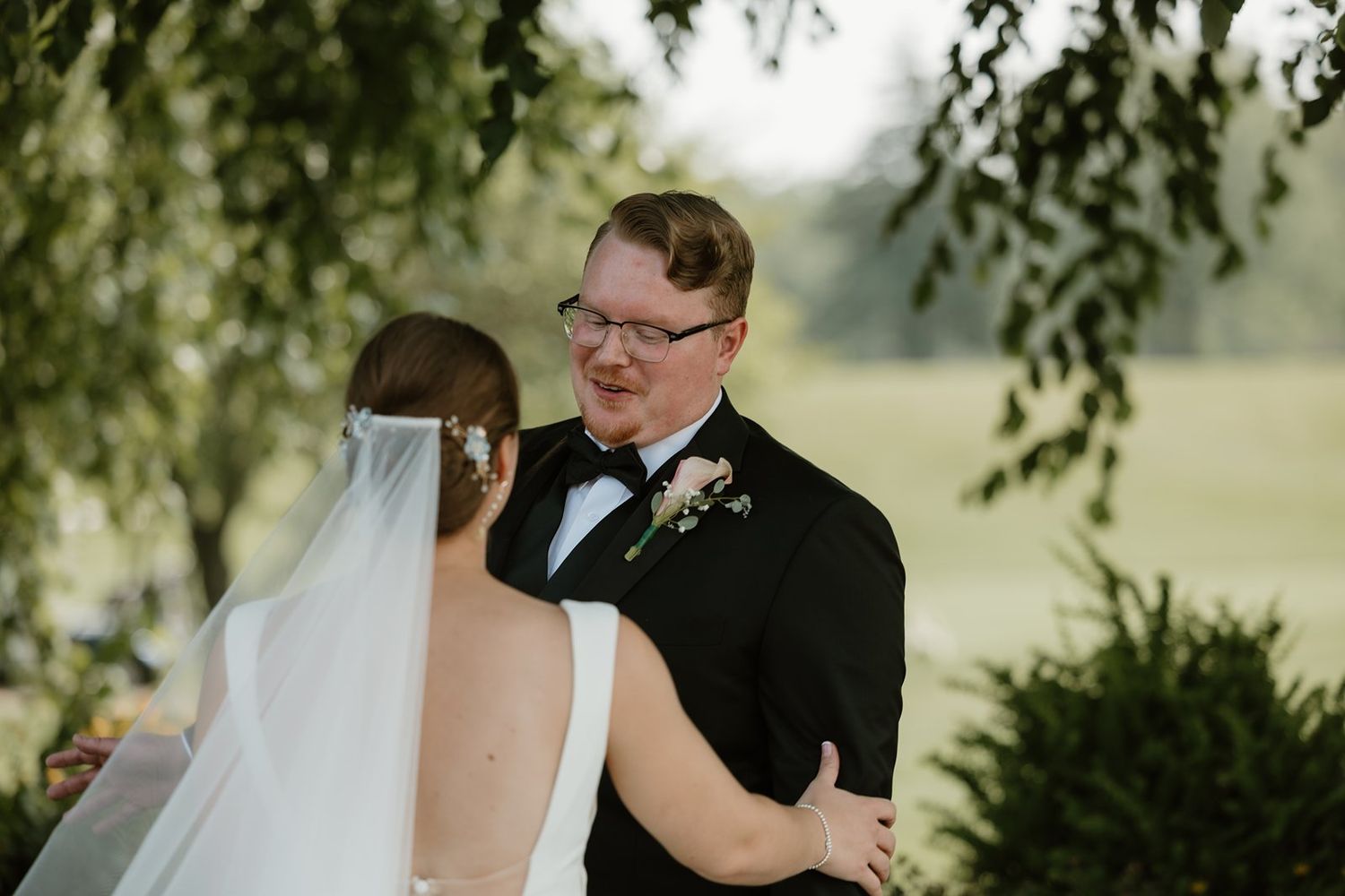 Bride and groom share intimate moments during outdoor wedding portraits under a weeping willow tree.