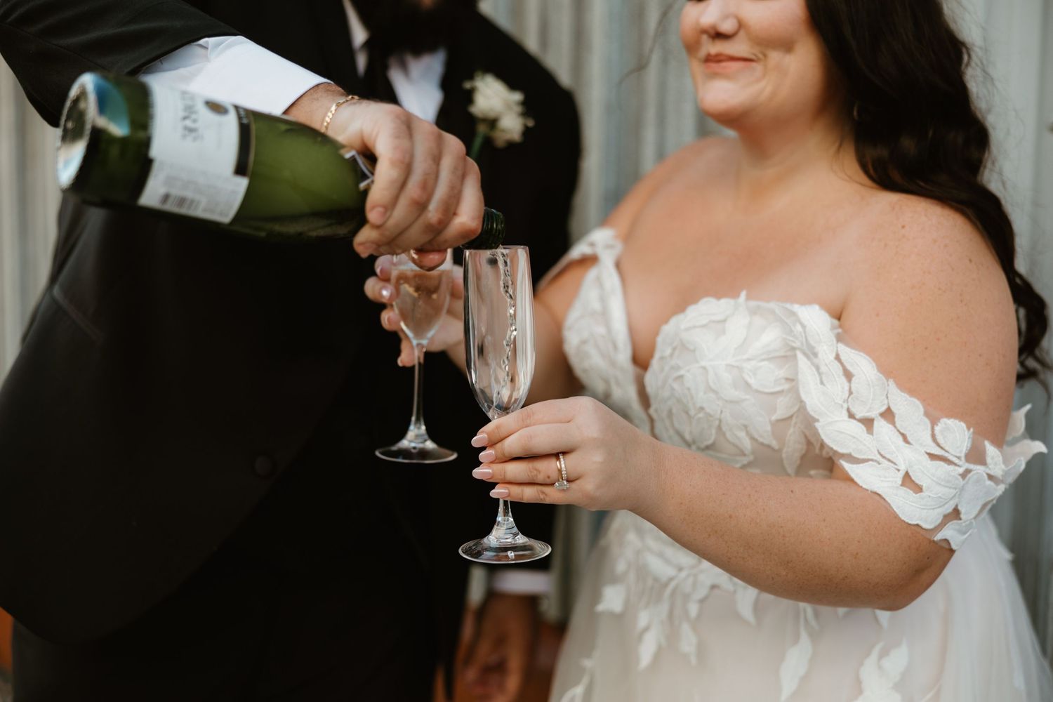 A champagne bottle being poured into glasses during a wedding celebration.