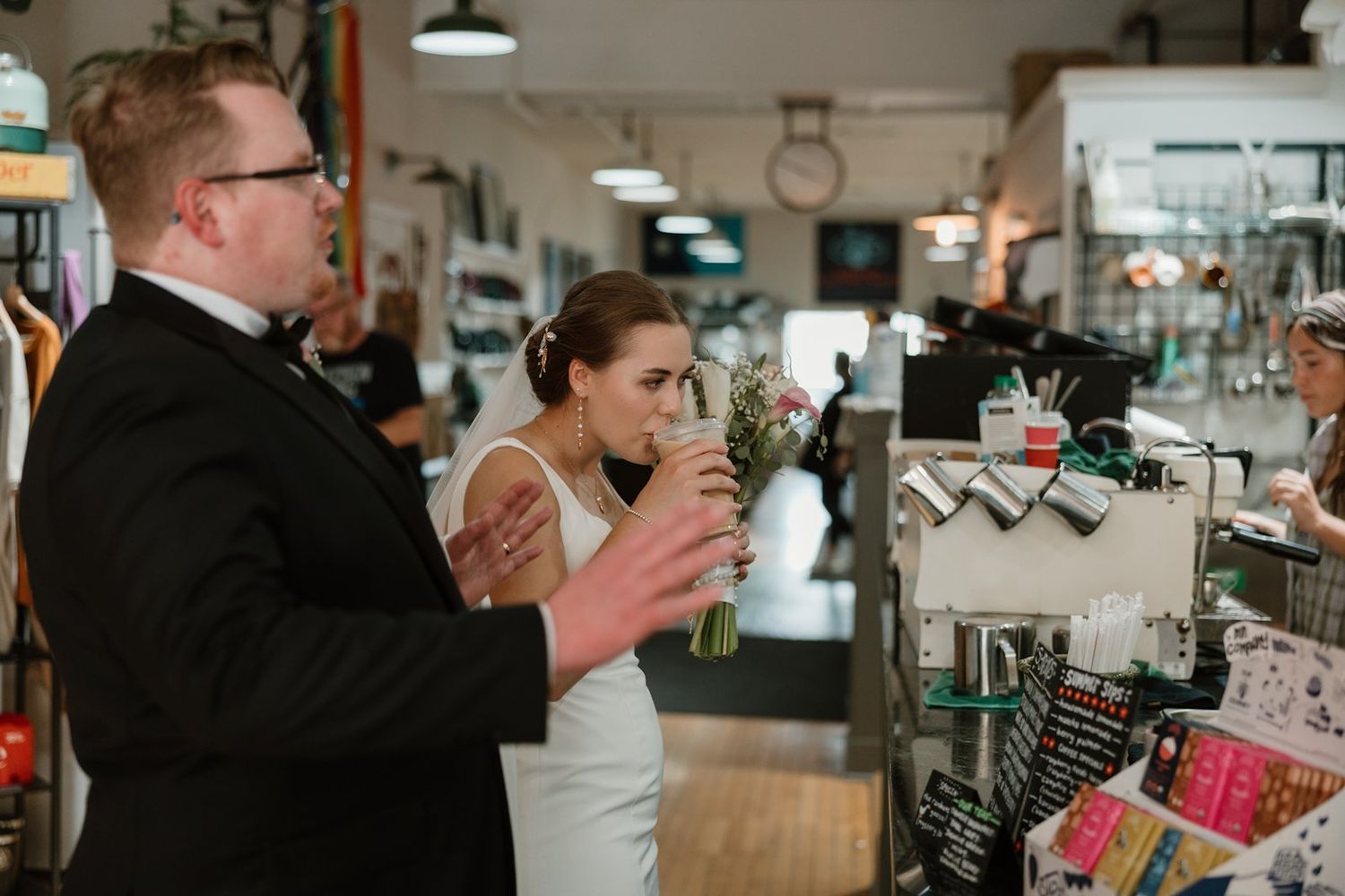 Customers browse and shop at a bustling modern coffee bar with industrial lighting and sleek decor.