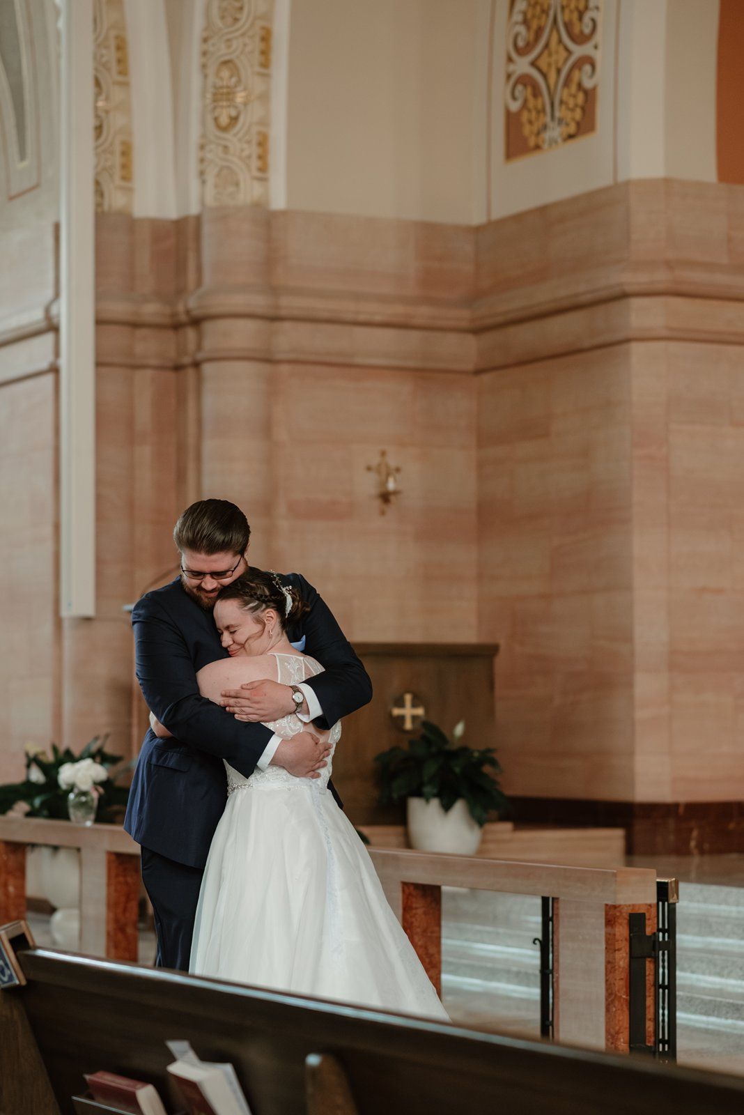 A romantic wedding couple shares a passionate kiss in a grand church with ornate architectural details.