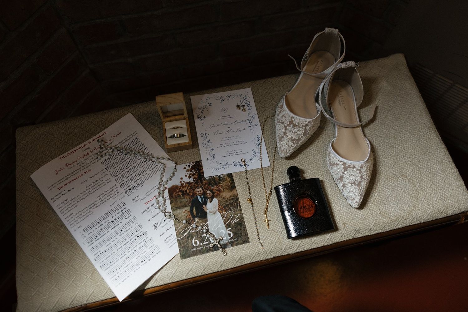 Wedding day accessories including white bridal shoes, photos, papers and jewelry displayed on a light surface.