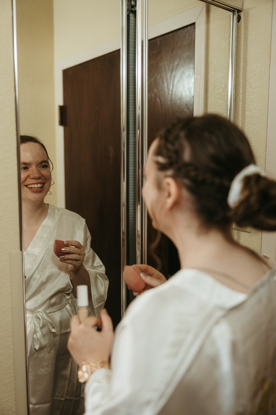 Three mirrored reflections show people in white robes getting ready in a bathroom interior.