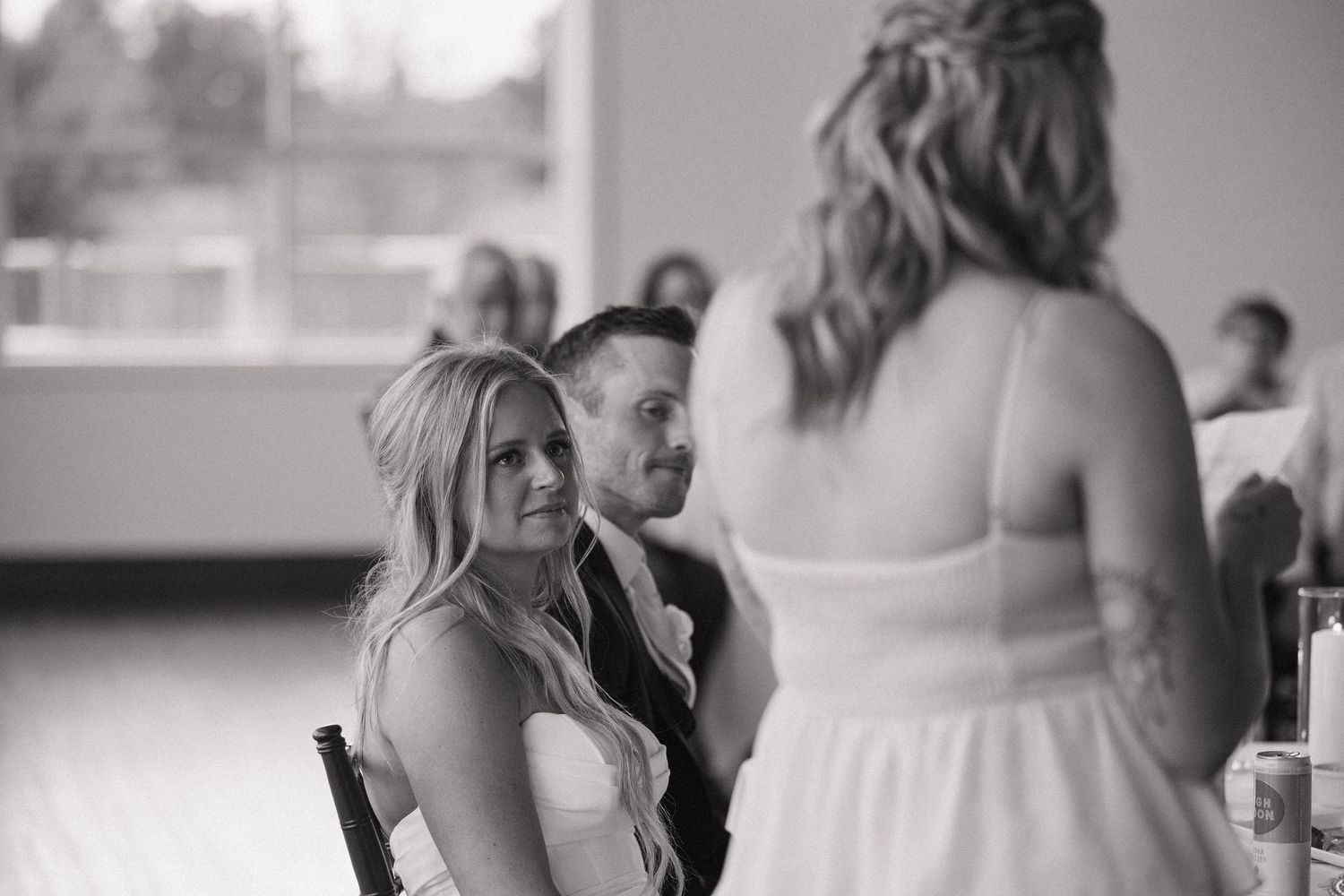 Black and white candid photo of wedding guests chatting at reception.