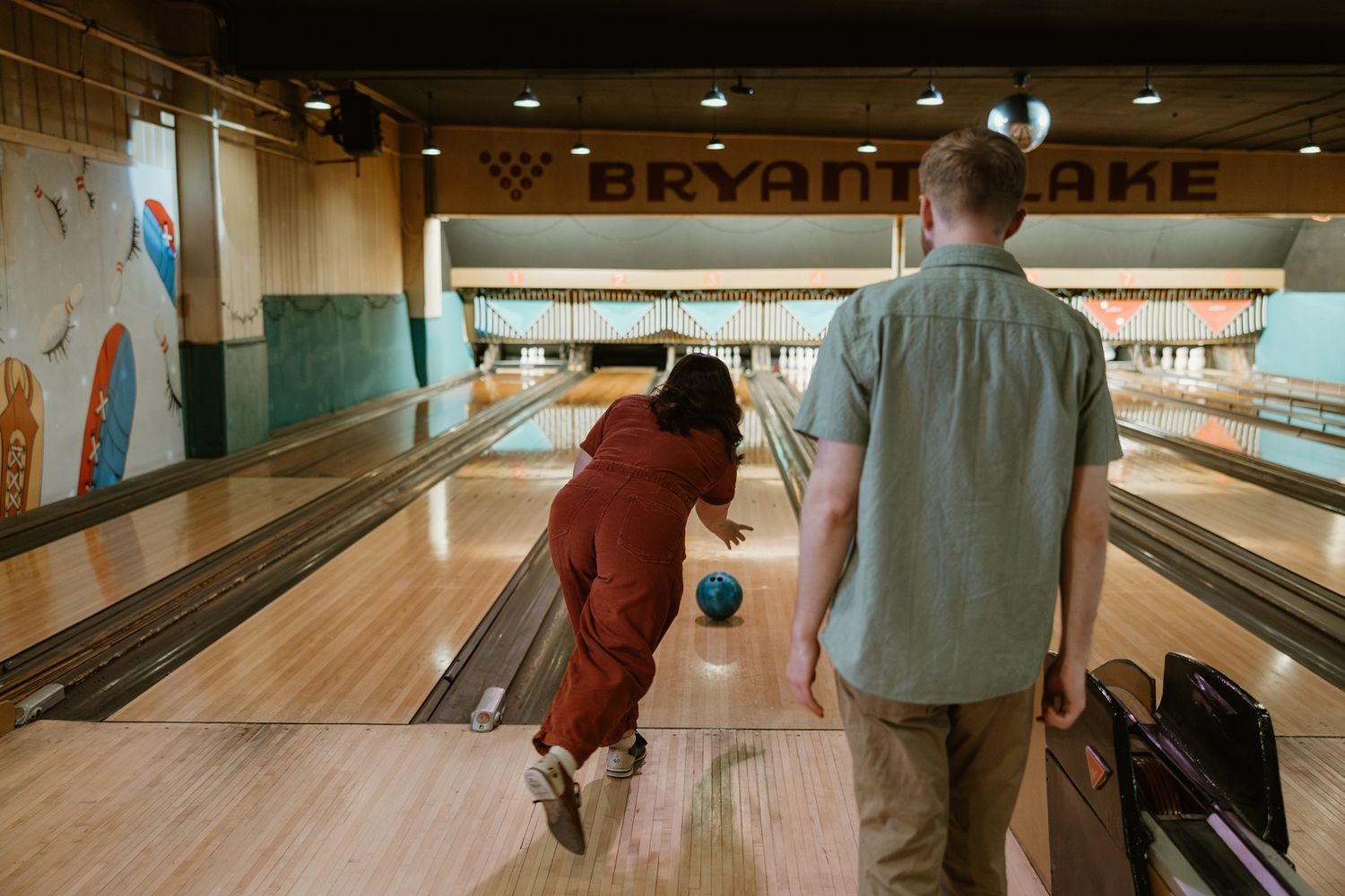 Two people bowling together at a retro bowling alley with wooden lanes and vintage decor.