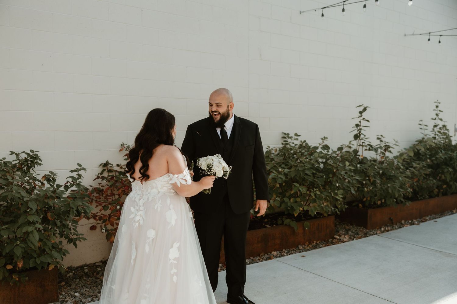 A couple shares a sweet moment together during their wedding day against a garden wall backdrop.