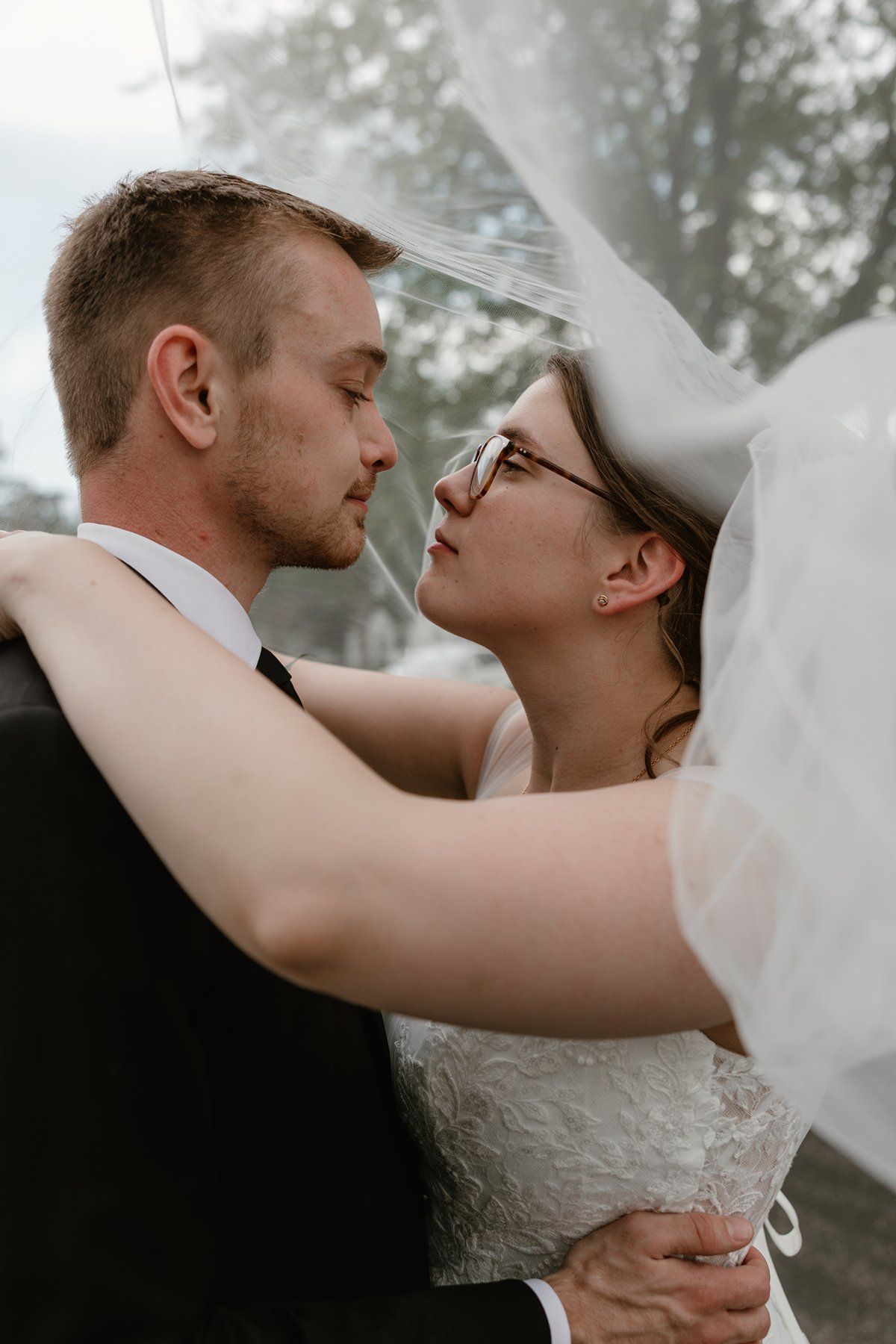 Intimate wedding portrait captures tender moments between newlyweds in a misty outdoor setting.