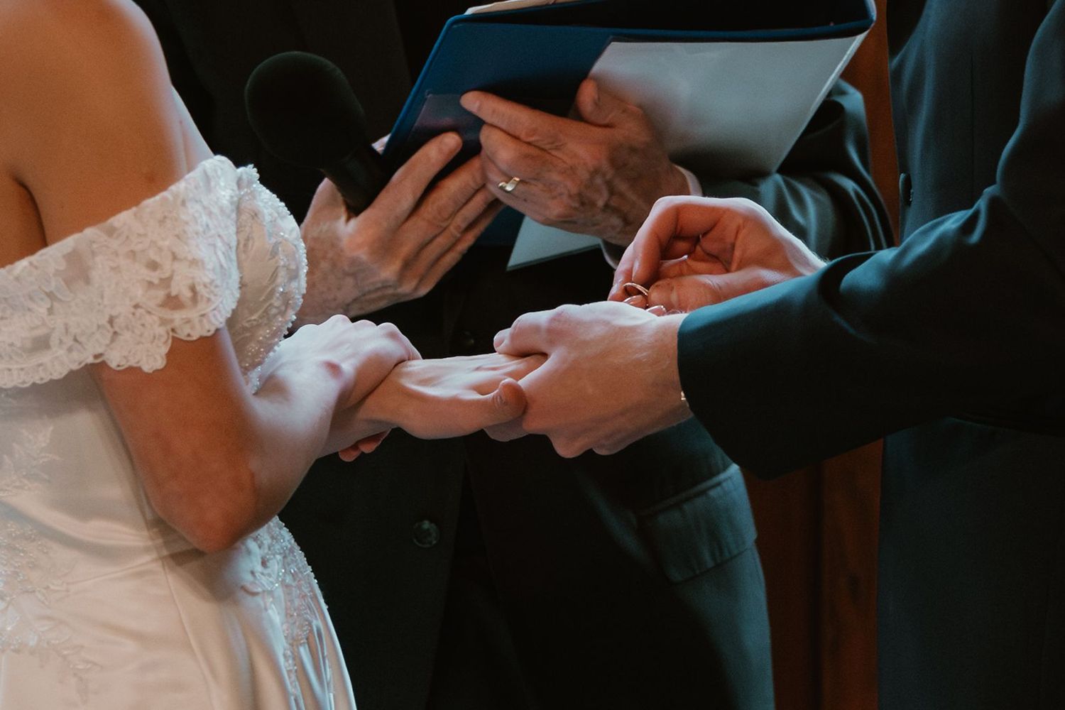 Close-up of hands exchanging rings during a wedding ceremony.