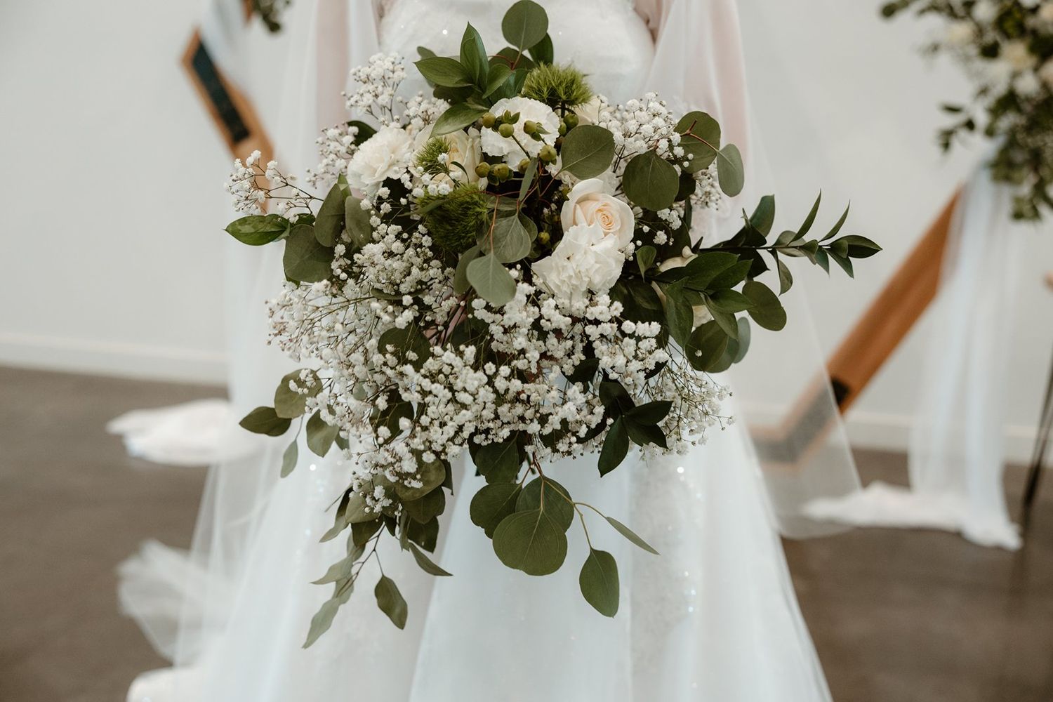 Elegant white wedding dress with lace details and eucalyptus bouquet photographed in natural light.