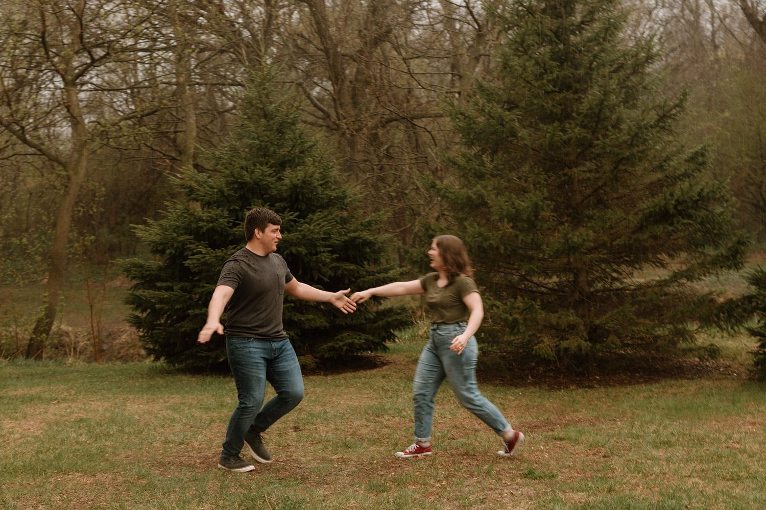 Dancing couple spins and twirls together in a scenic wooded park area.
