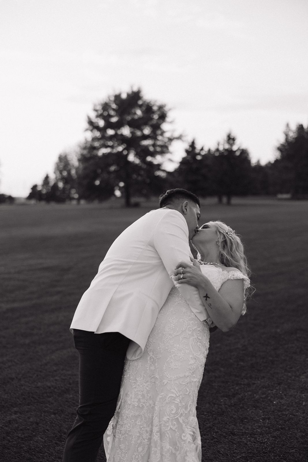 A black and white romantic moment between newlyweds on a golf course.
