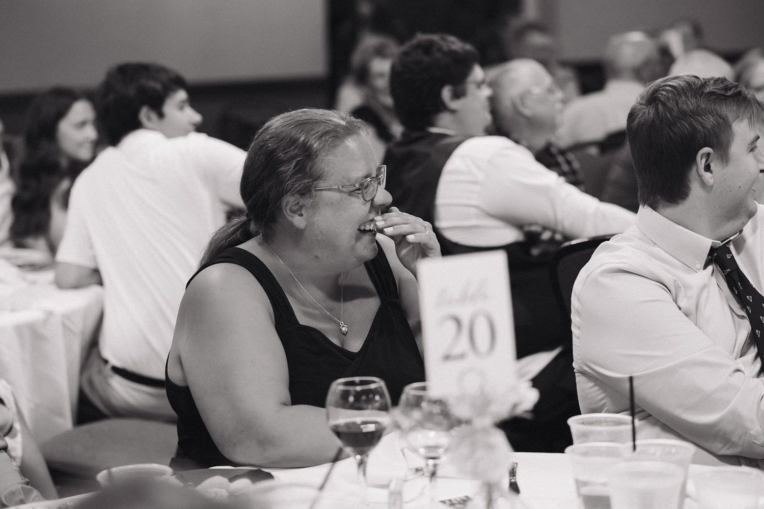 A black and white photograph shows people seated at dining tables during what appears to be a banquet or conference event.