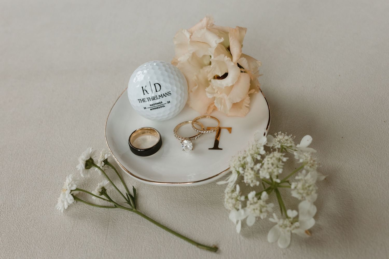 A delicate arrangement of white roses and small flowers on a light beige surface with soft natural lighting.