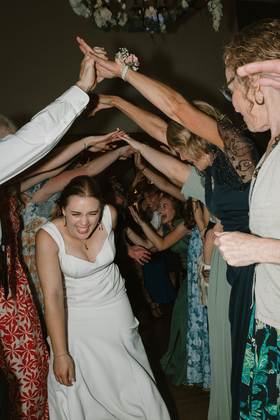 Wedding party dancing and celebrating on a crowded dance floor at an evening reception.