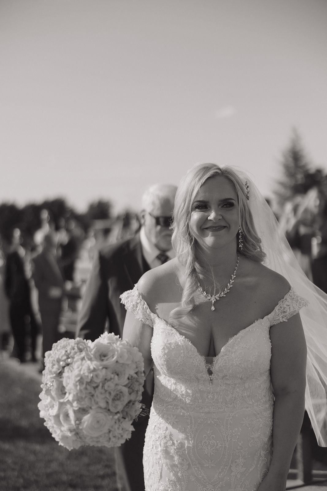 Black and white portrait of a radiant bride holding a luxurious bouquet.