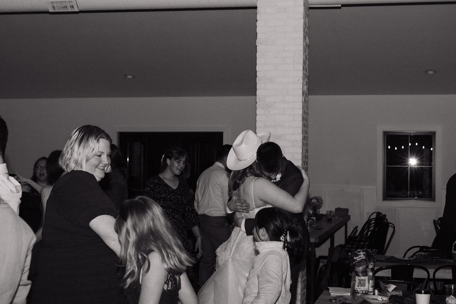 Dark interior view of a party space with people mingling and dancing under low lighting conditions.