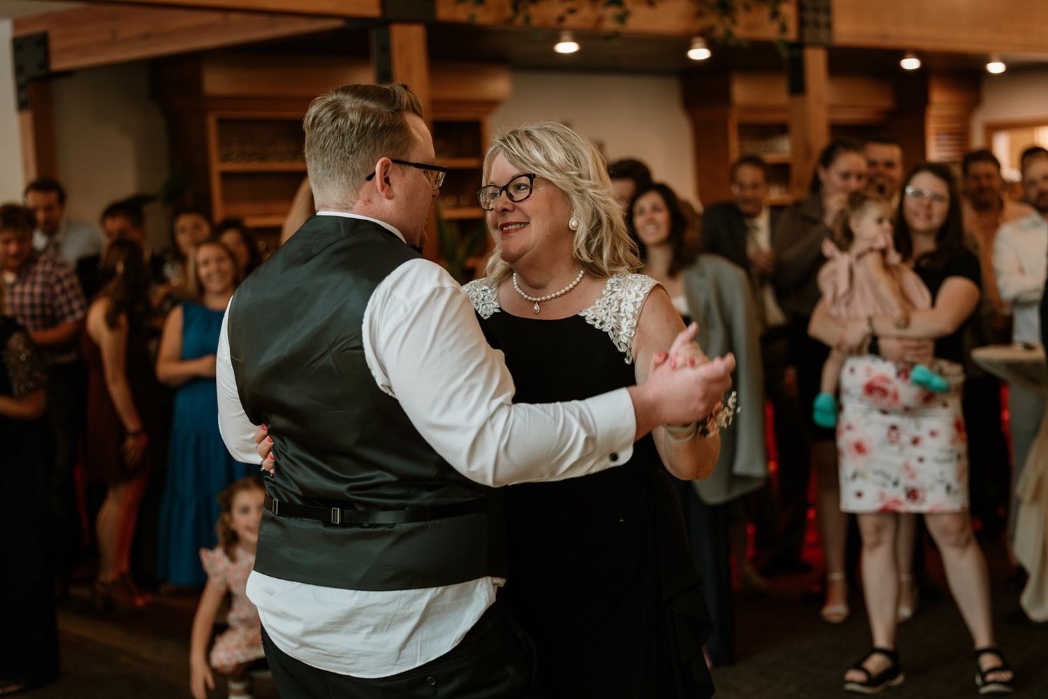 Guests dance and celebrate at a lively wedding reception with warm lighting and festive atmosphere.