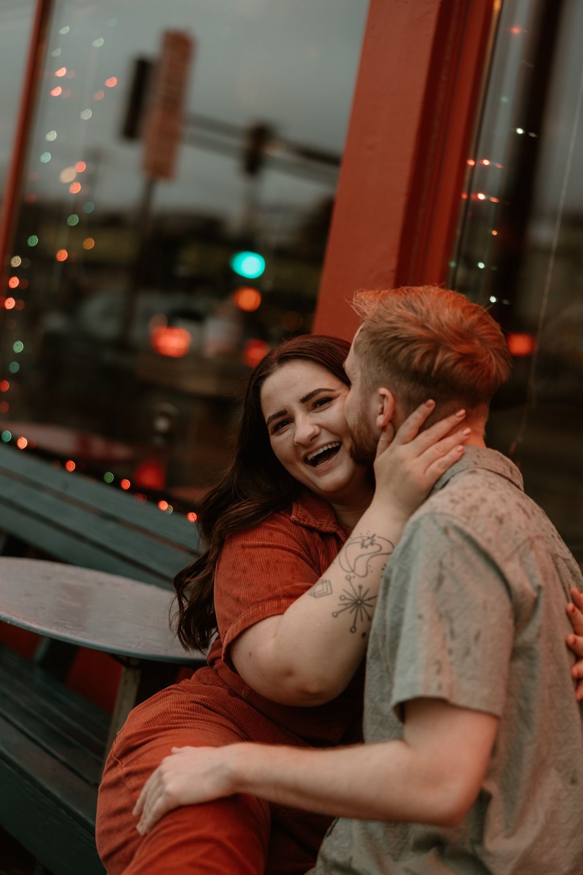 A couple shares an intimate moment in a dimly lit room with twinkling lights in the background.