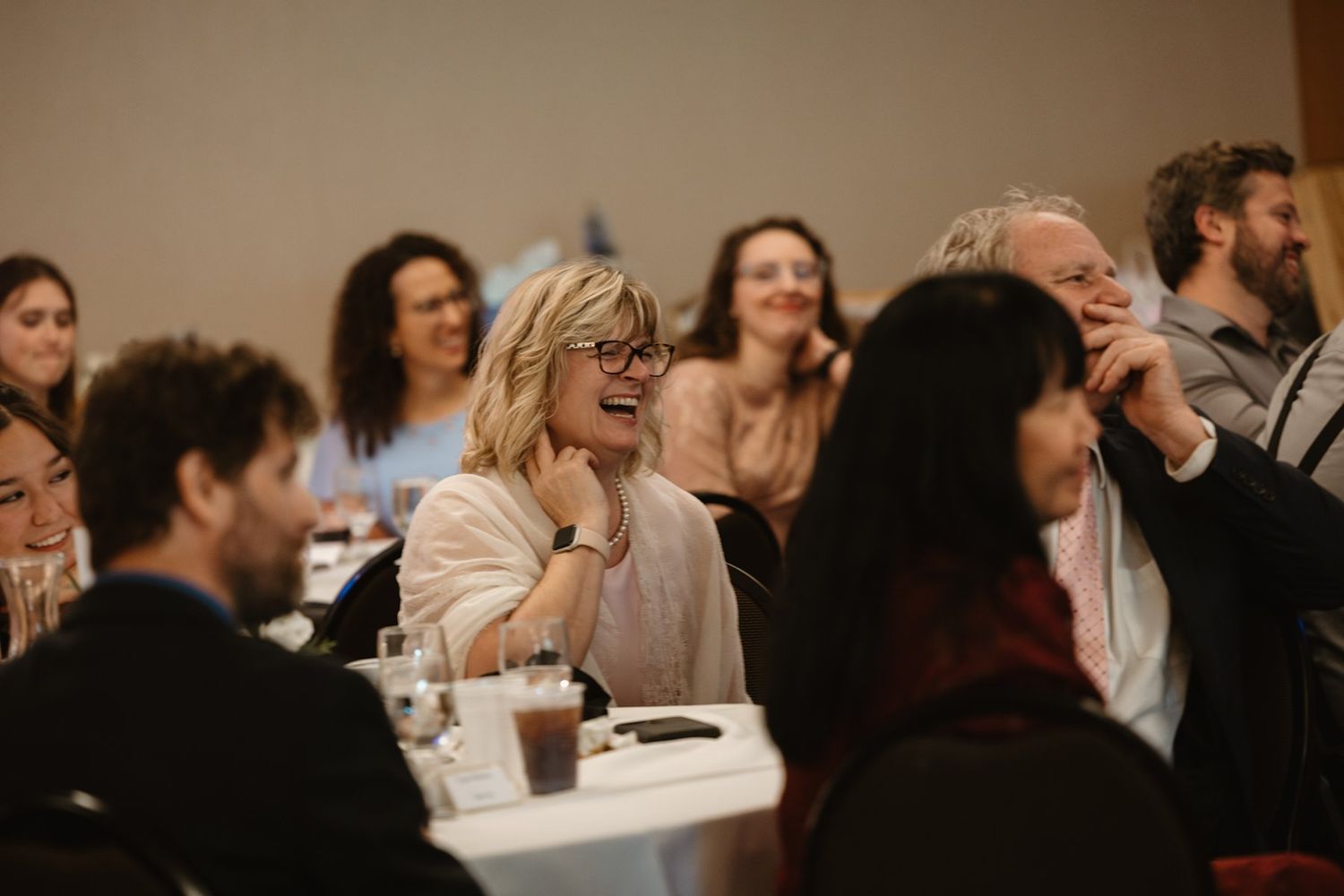 People engage in lively conversation while seated at tables during what appears to be a social event or gathering.
