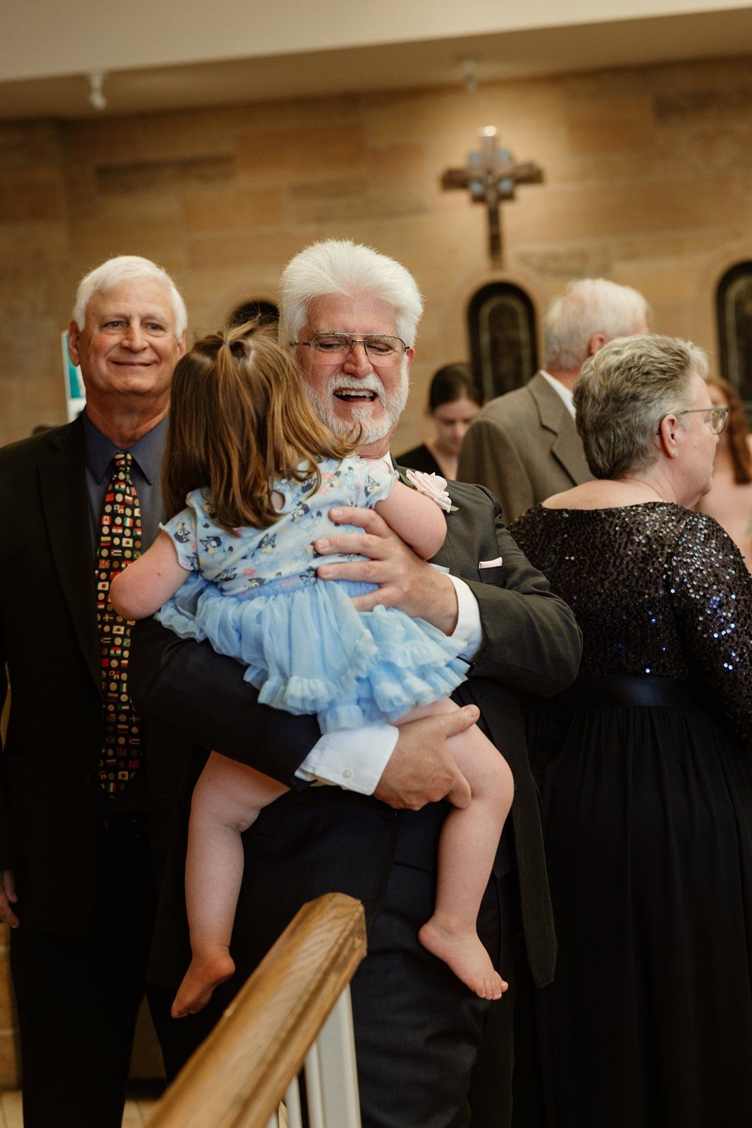 Wedding reception guests gather and celebrate with a small child in blue outfit.