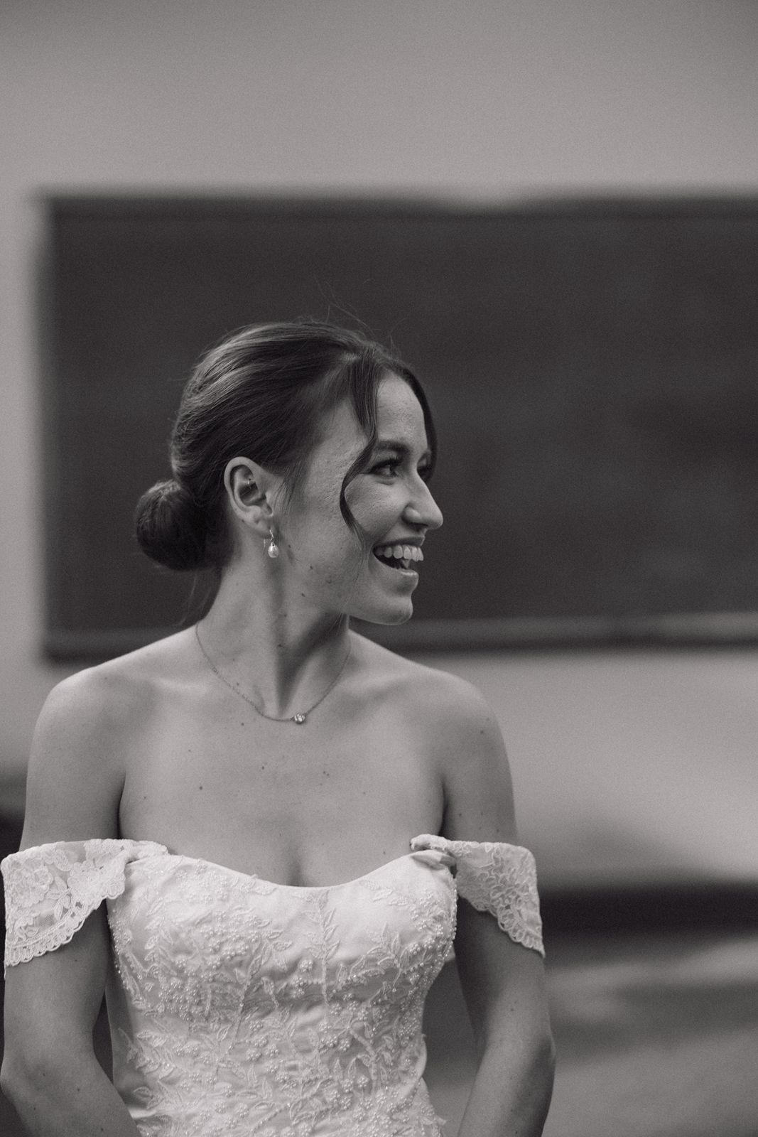 Black and white portrait of bride in off-shoulder lace wedding dress.