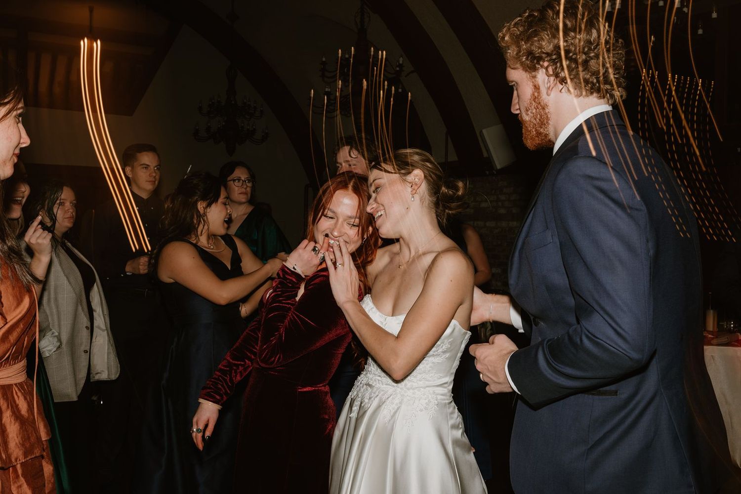 Wedding guests dancing and celebrating in a venue with arched ceilings.