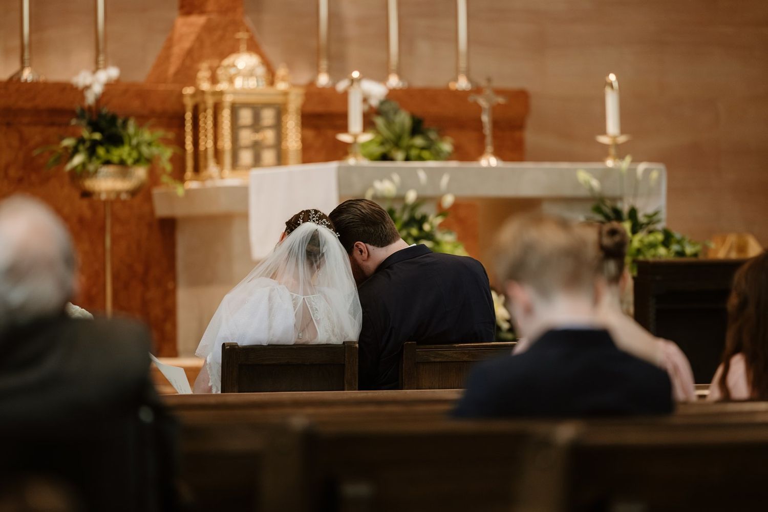 Elegant church interior with warm lighting and wooden details during a wedding ceremony.