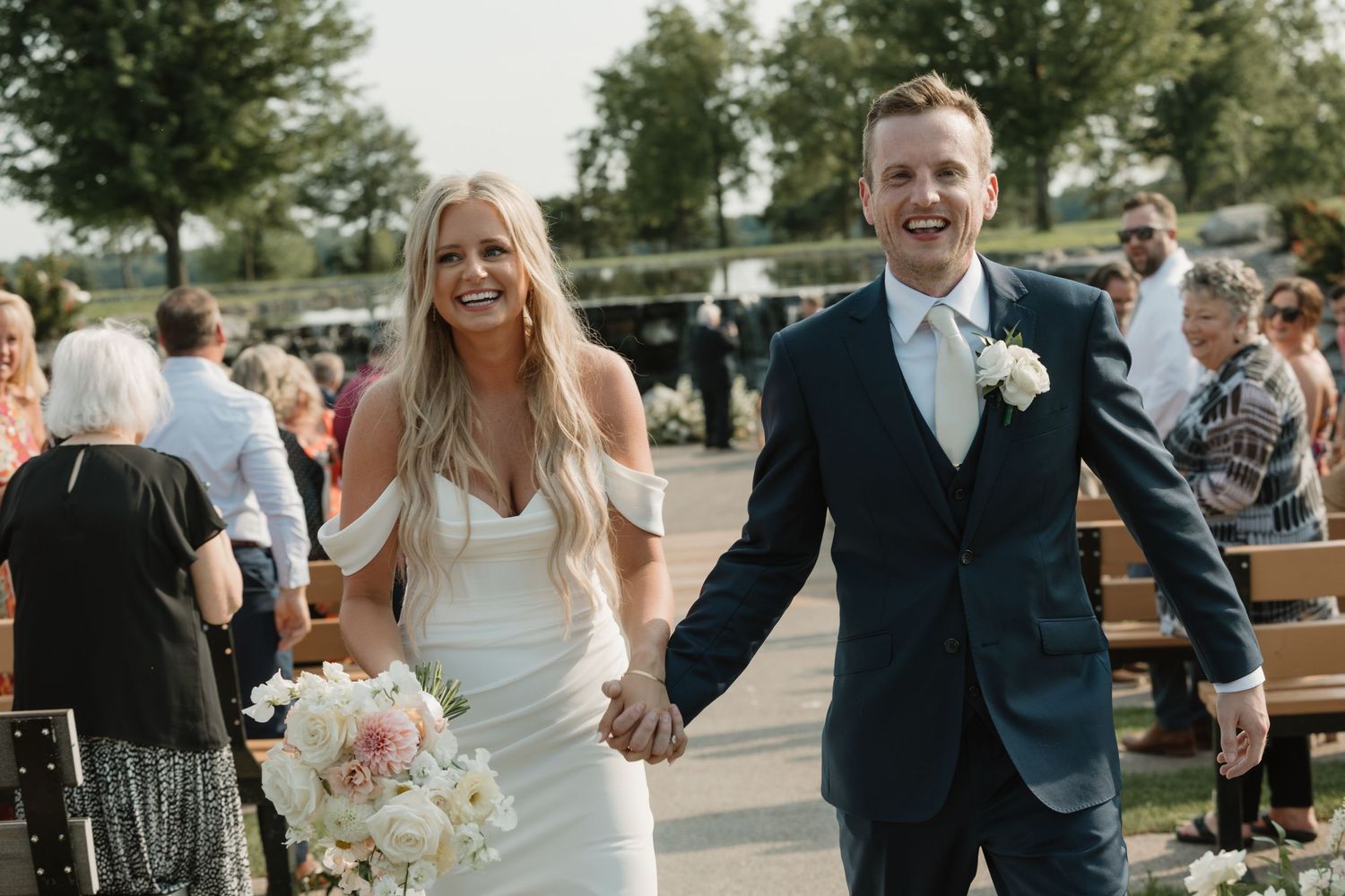 A group celebrates at an outdoor wedding reception on a sunny day with guests mingling on a patio.