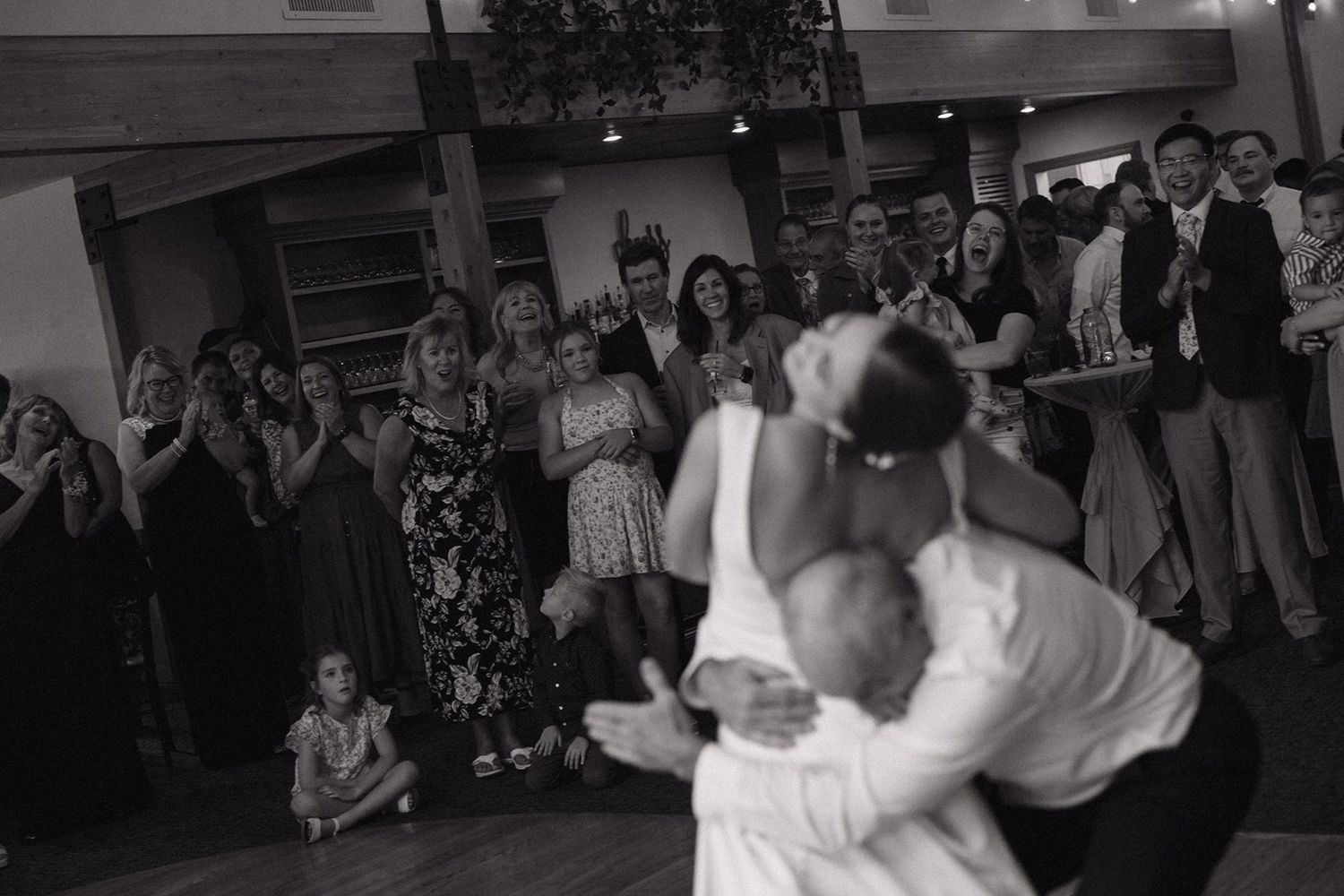 A couple performs their first dance at a wedding reception while guests watch from the sidelines.