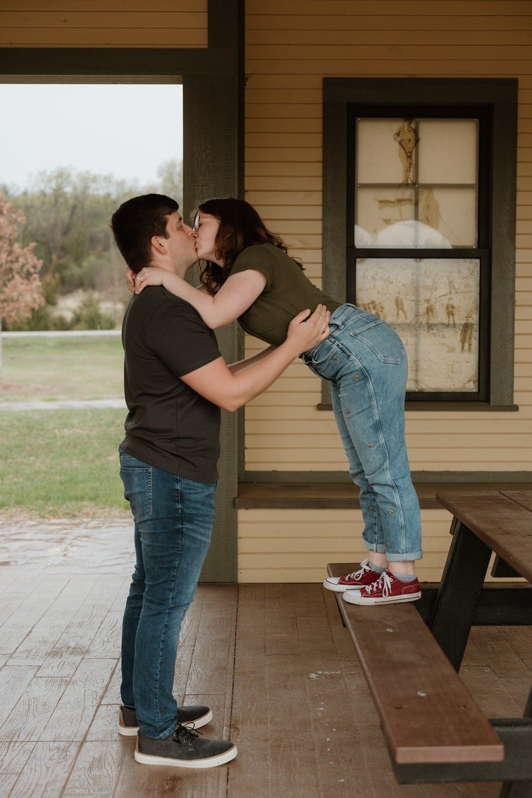 A couple shares a romantic moment on a rustic wooden porch, creating a series of affectionate poses.