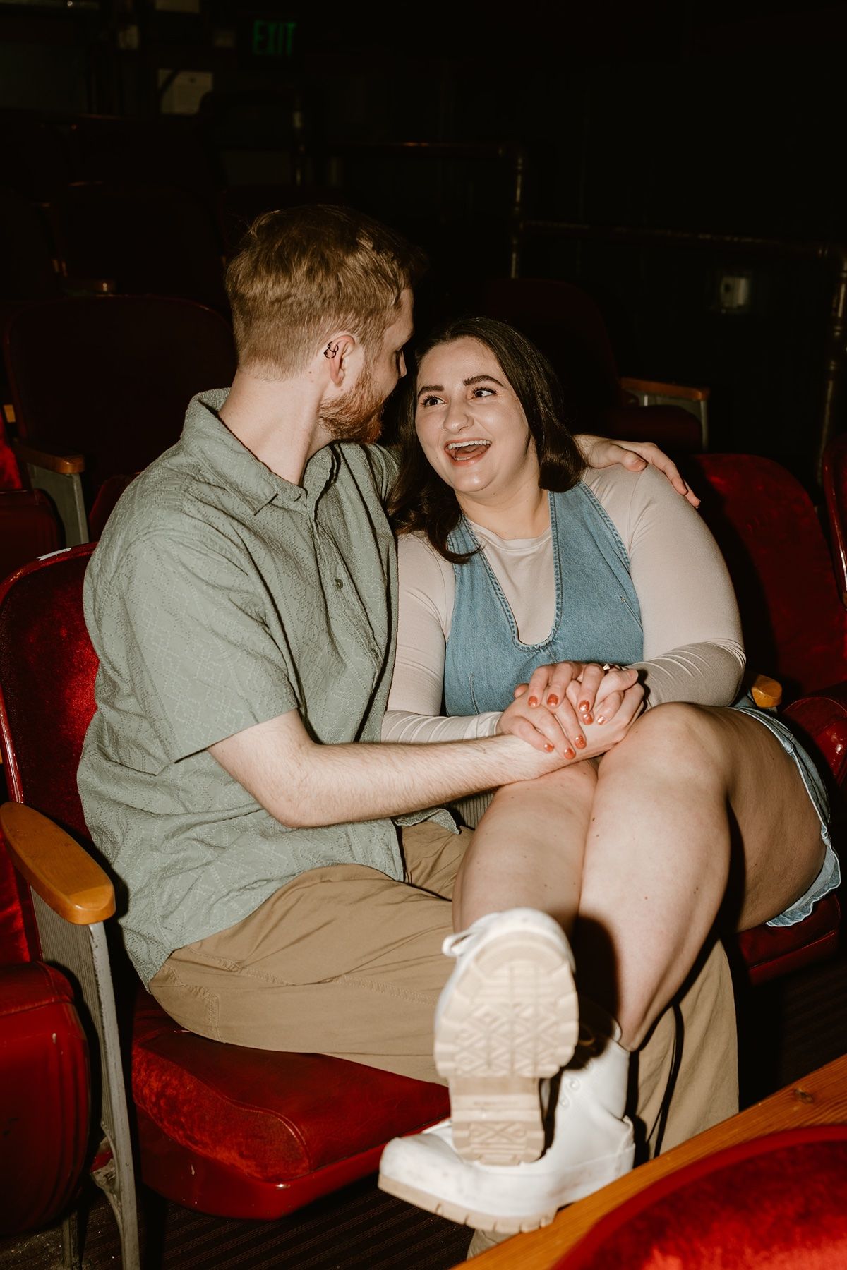 A sequence of photos showing a couple sitting in red theater seats sharing an intimate moment together.