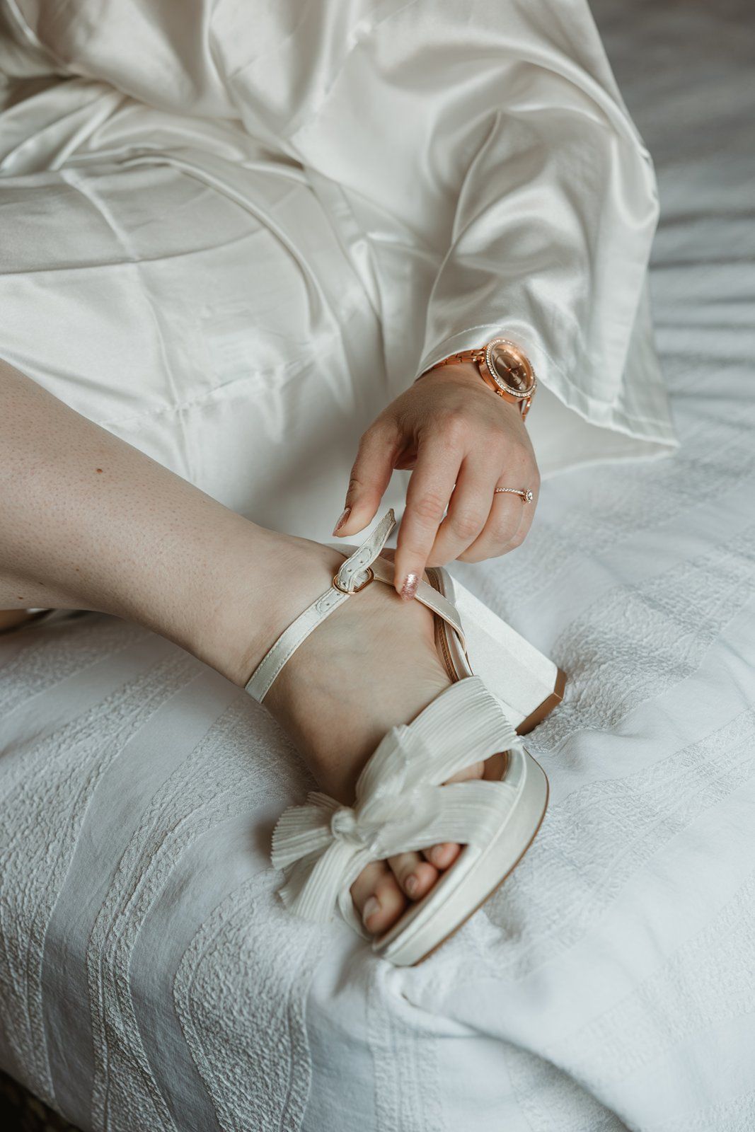 Delicate hands adorned with rings rest on white lace fabric in a romantic vintage style composition.