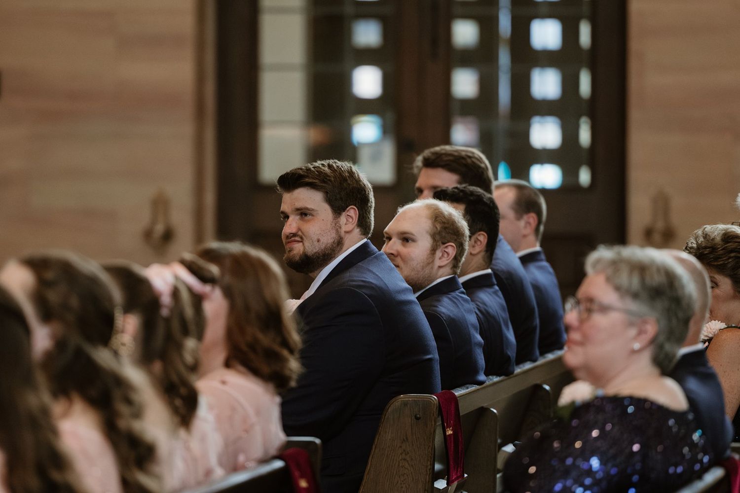 Wedding guests seated in church pews watching the ceremony proceedings.