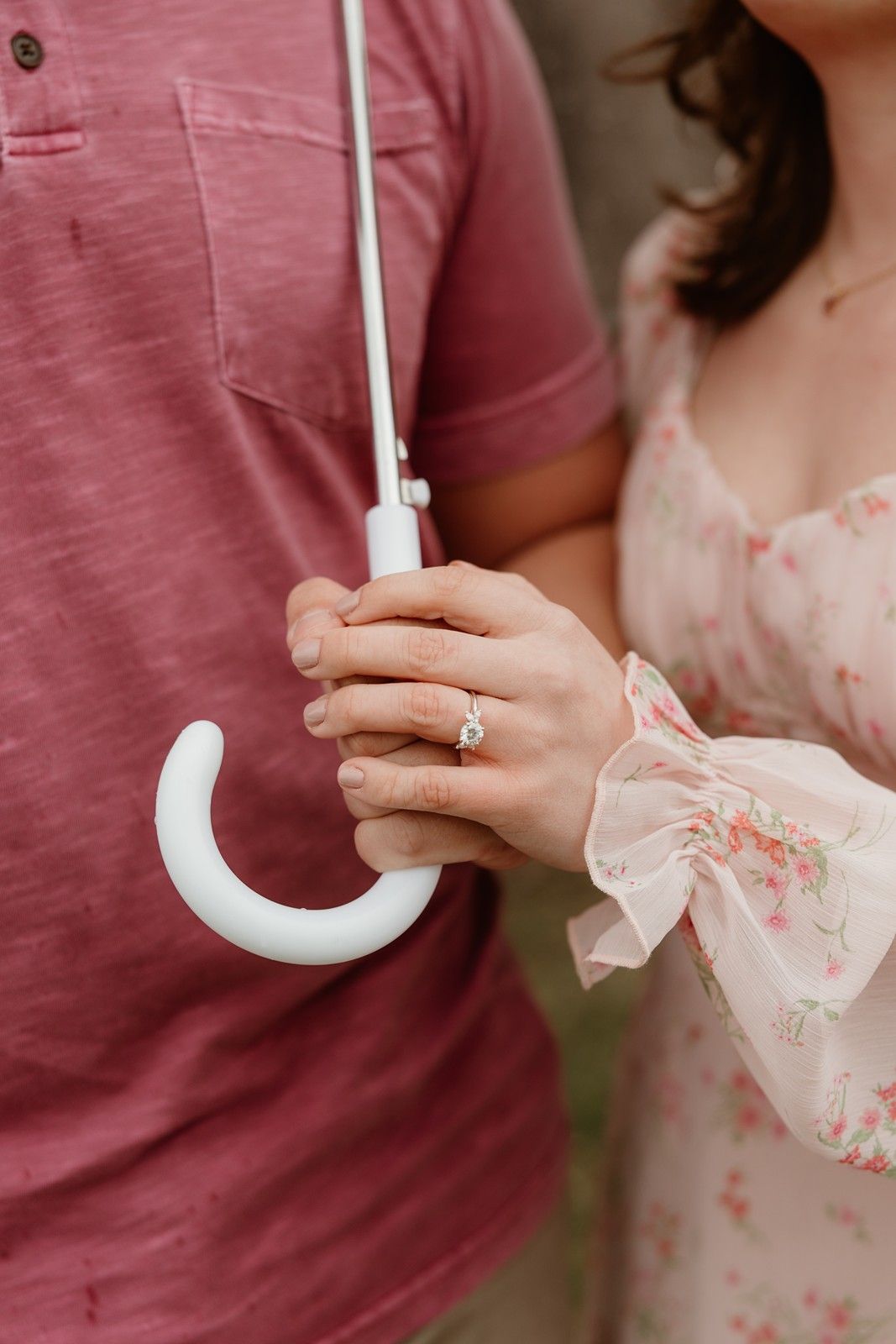 Two hands wearing wedding rings reach for each other in tender moment against pink background.