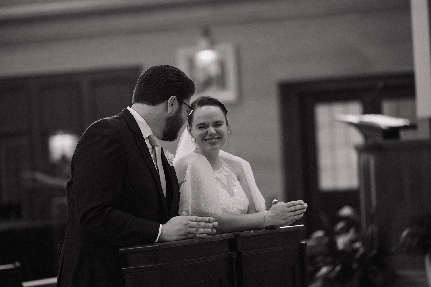 Black and white photo of people seated in church pews during a service.