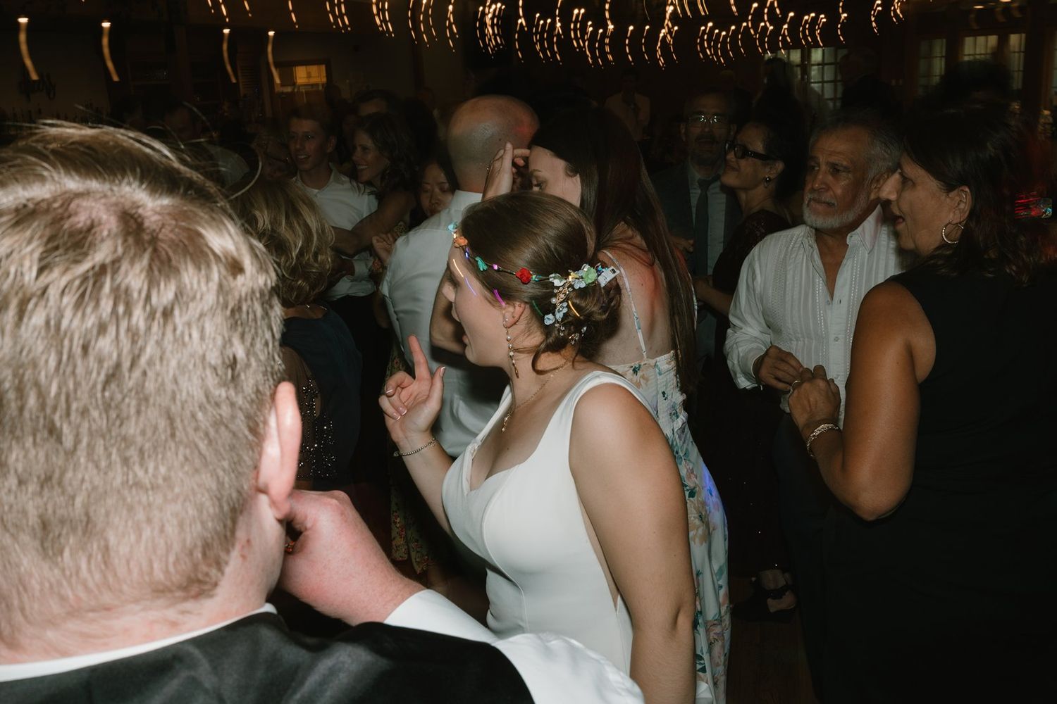 Silhouettes of people dancing with raised arms at a wedding reception party.