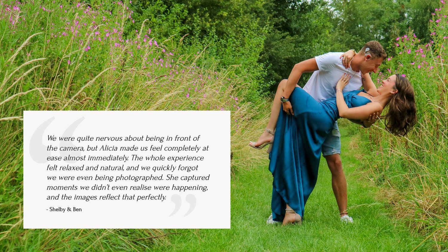 A couple embraces in a romantic pose amidst lush green grass and natural scenery.