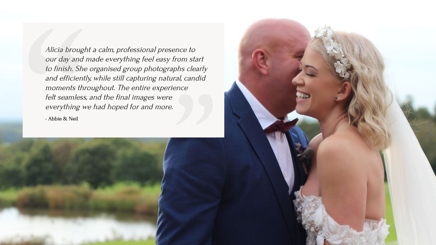 A bride and groom share a joyful moment together outdoors with a lake in the background.