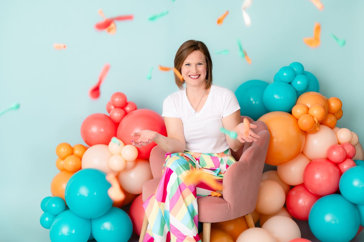 A celebratory scene with colorful balloons in coral, turquoise and orange against a light blue background.